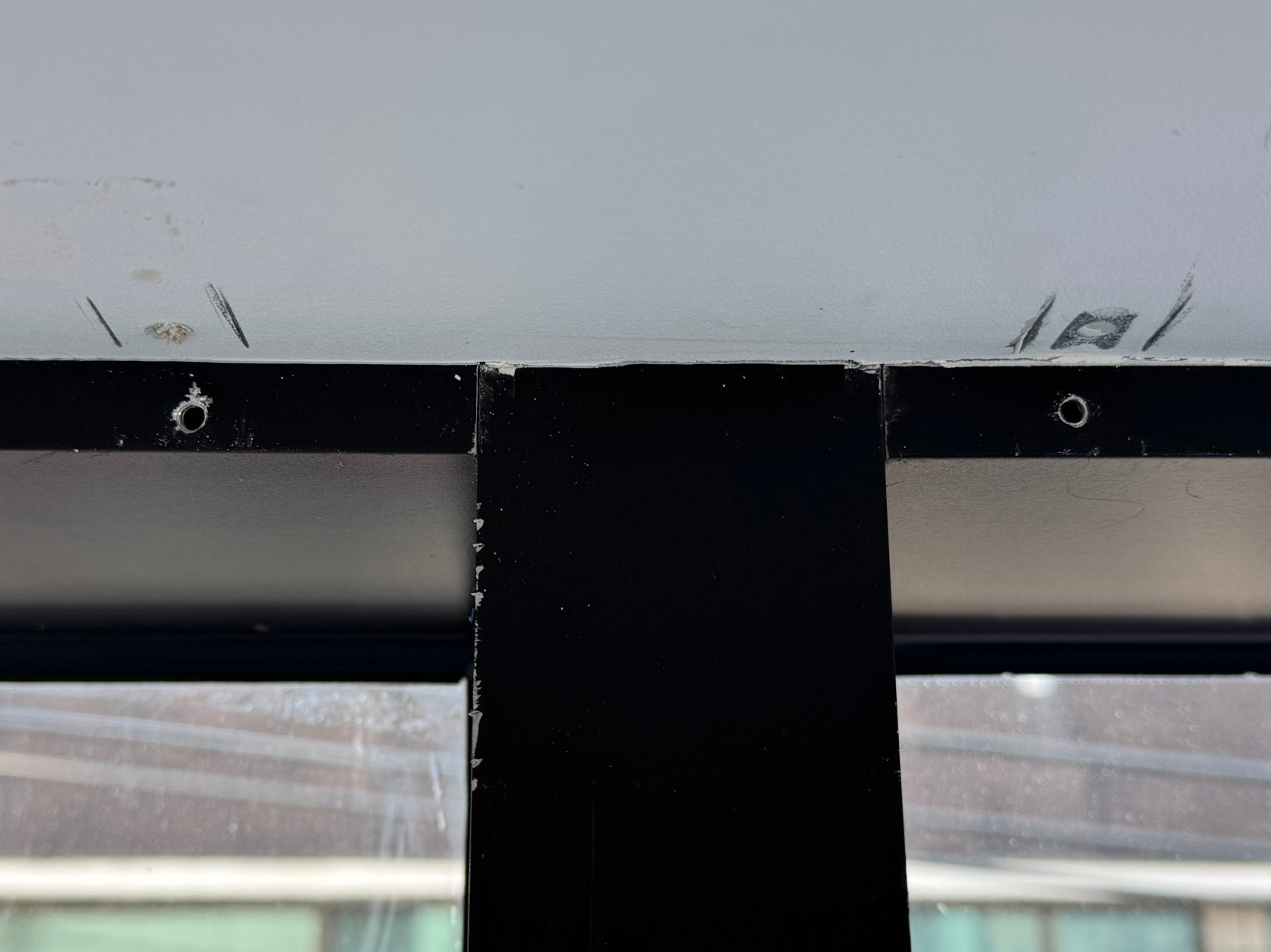 서울 강남구 논현동 상가의 검은색 알루미늄 샷시에 블라인드 브라켓과 도어락 철거 후 타공 구멍이 남아 있다. 샷시 전문 복원 업체 프로샷시가 구멍을 보강하고 기존 색상과 광택에 맞춰 자연스럽게 원상복구했다.